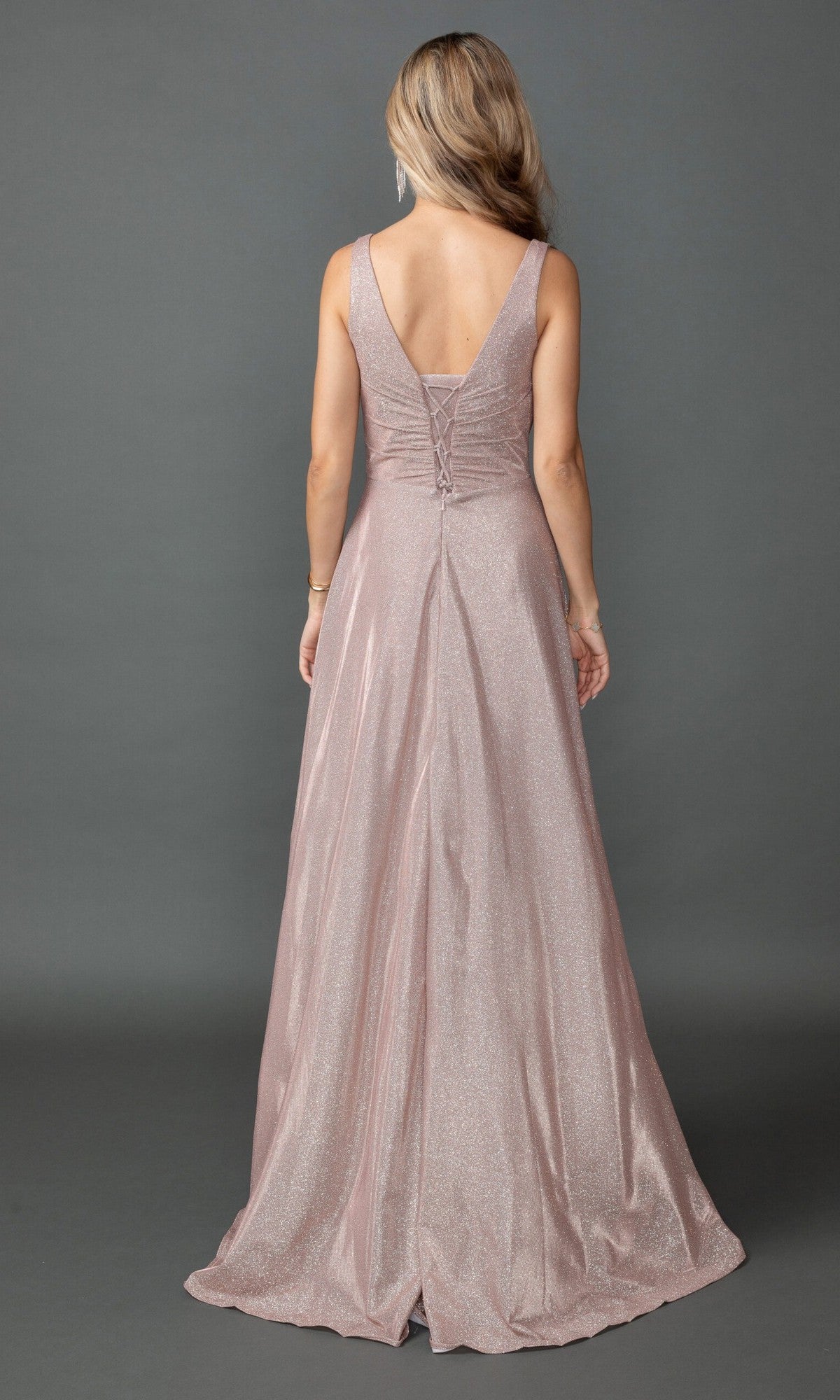 A woman stands with her back to the camera in the Dancing Queen 4545, a sleeveless, floor-length pink glitter prom dress with an A-line silhouette, V-back, and lace-up detail.